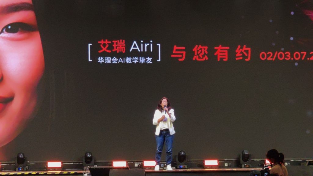 Tina Leon on stage at the MCLC AI-Empowered Education workshop, introducing the 'Airi' interactive AI Avatar, who is presented on the large screen behind her as an AI teaching companion.
